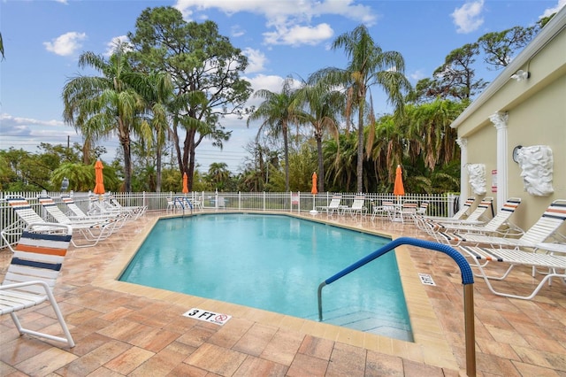 community pool with fence and a patio