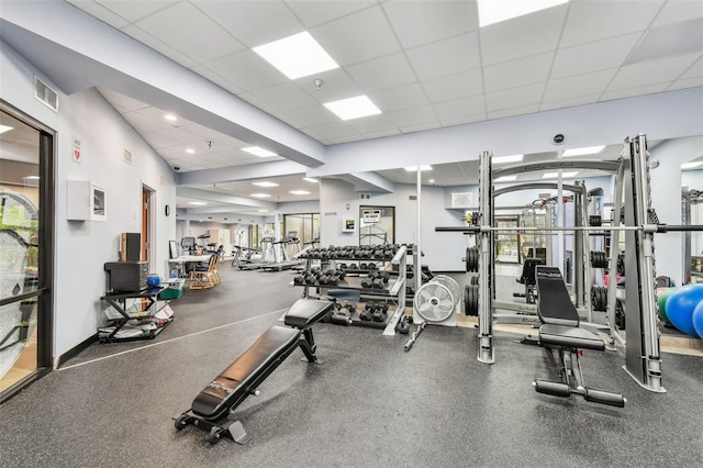 workout area featuring a paneled ceiling, visible vents, and baseboards