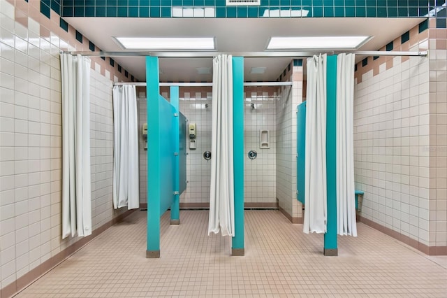 bathroom with tile patterned flooring, a tile shower, and tile walls