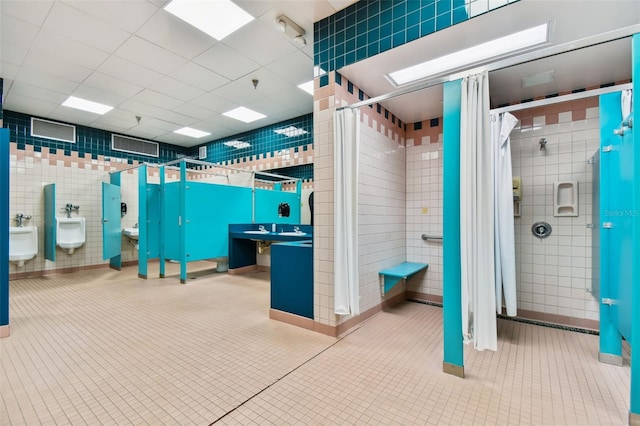 interior space with a bidet, a shower stall, tile walls, and tile patterned floors