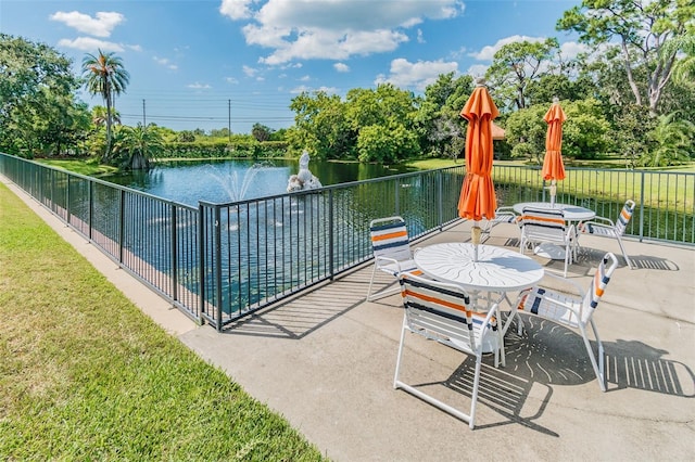 view of swimming pool with a water view, fence, and a yard