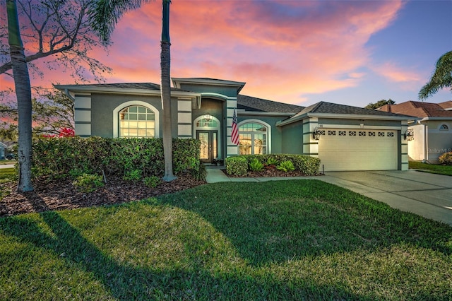 view of front of house with a front yard, concrete driveway, an attached garage, and stucco siding