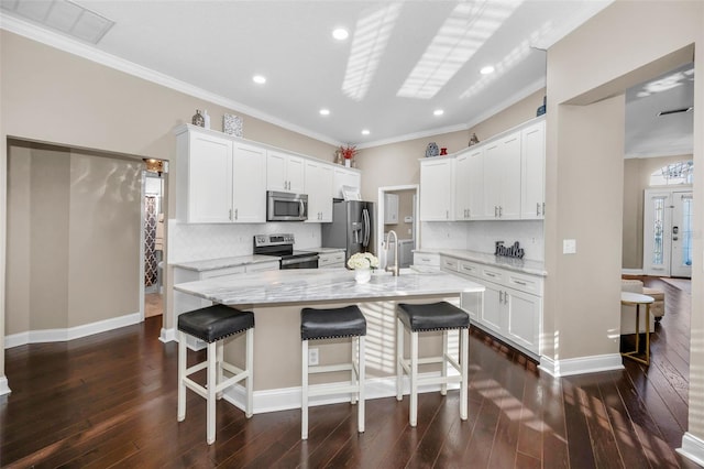 kitchen with appliances with stainless steel finishes, dark wood-style flooring, a breakfast bar, and white cabinets