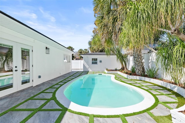 view of swimming pool featuring a patio area, a fenced backyard, a fenced in pool, and french doors