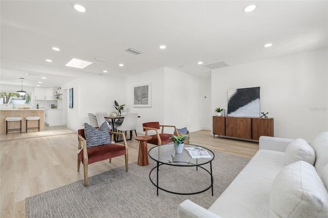 living room featuring recessed lighting, a skylight, visible vents, and light wood-style floors