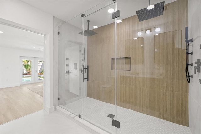 full bathroom with a stall shower, french doors, baseboards, and wood finished floors