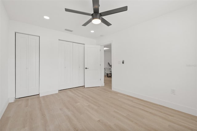 unfurnished bedroom with multiple closets, recessed lighting, visible vents, light wood-style floors, and baseboards