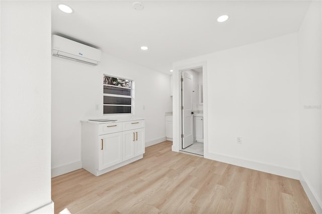 empty room featuring a wall unit AC, light wood finished floors, and recessed lighting