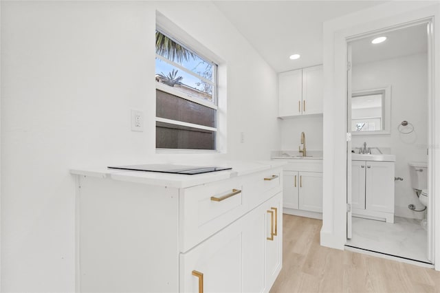 kitchen featuring recessed lighting, light countertops, light wood-style floors, white cabinets, and black electric cooktop