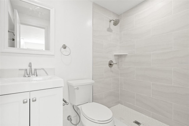 full bathroom featuring tiled shower, vanity, and toilet