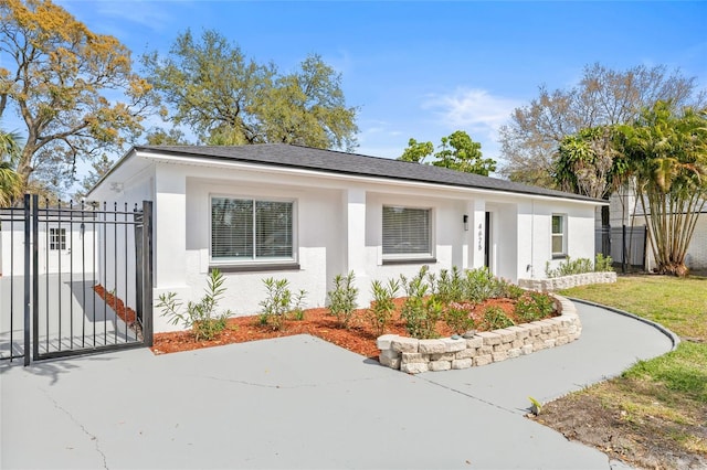 view of front of property featuring a shingled roof, fence, a gate, and stucco siding