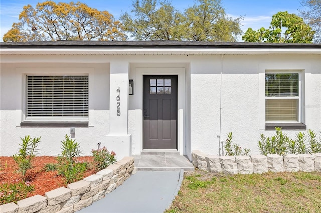 doorway to property featuring stucco siding