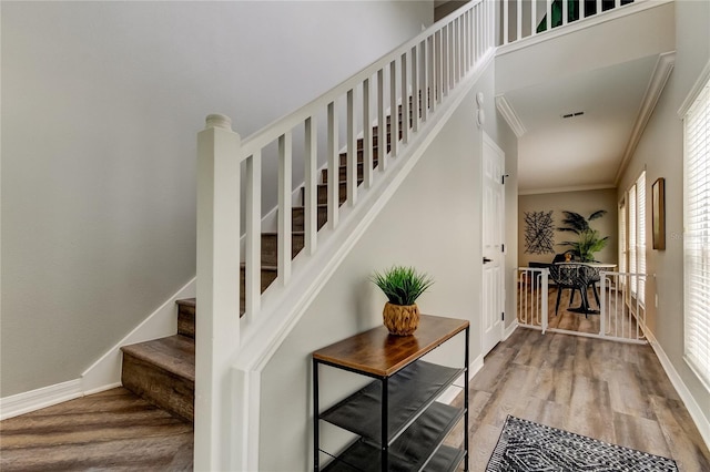 stairway featuring ornamental molding, wood finished floors, visible vents, and baseboards