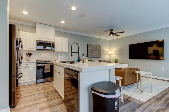 kitchen with a center island with sink, visible vents, white cabinets, stainless steel appliances, and light countertops