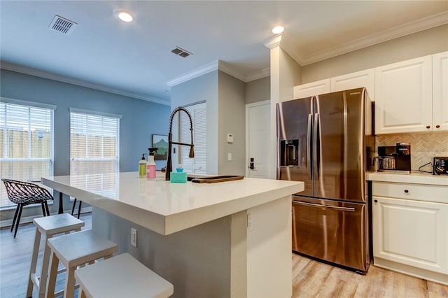 kitchen with a kitchen island with sink, visible vents, white cabinets, light countertops, and stainless steel refrigerator with ice dispenser