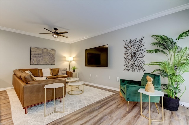 living area featuring ornamental molding, ceiling fan, baseboards, and wood finished floors