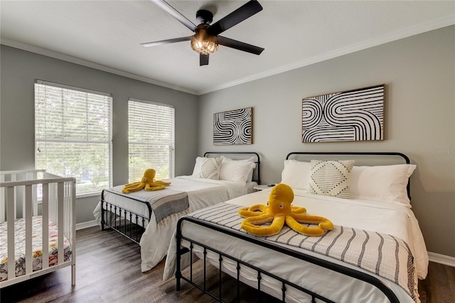 bedroom with dark wood-type flooring, crown molding, baseboards, and a ceiling fan