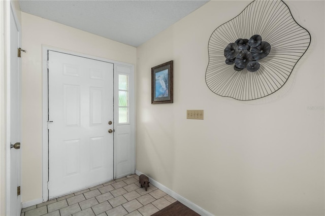 foyer entrance with baseboards and a textured ceiling