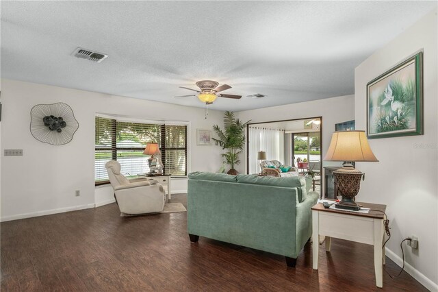 living area featuring visible vents, a textured ceiling, baseboards, and wood finished floors