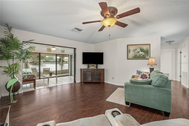 living area with a ceiling fan, a textured ceiling, visible vents, and wood finished floors