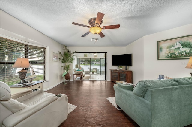 living area featuring plenty of natural light, visible vents, ceiling fan, and wood finished floors