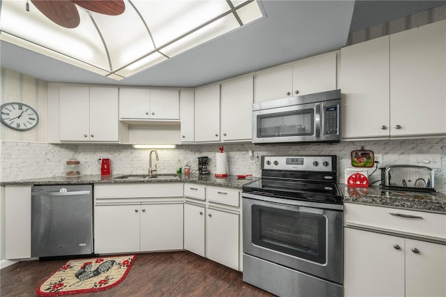 kitchen with stainless steel appliances, a sink, decorative backsplash, and dark wood-style floors