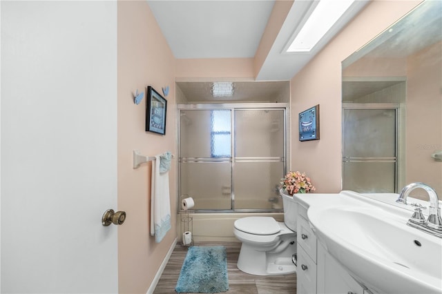 full bath with combined bath / shower with glass door, vanity, toilet, and wood finished floors