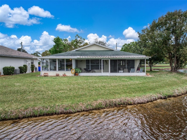 back of house with central AC unit, a water view, a sunroom, a yard, and roof with shingles