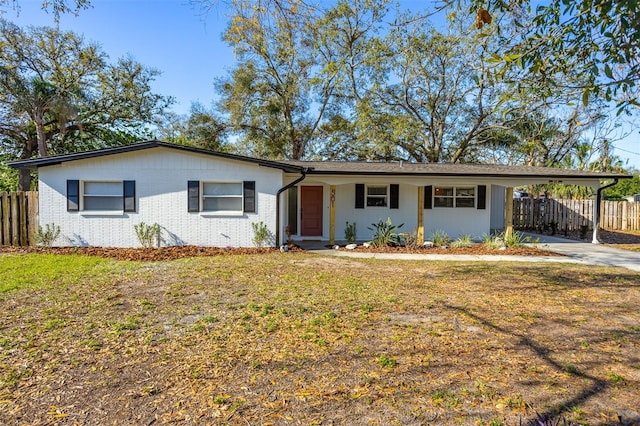 ranch-style house featuring a front yard, fence, an attached carport, and brick siding