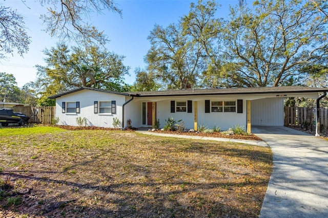 ranch-style house with an attached carport, brick siding, fence, driveway, and a front yard