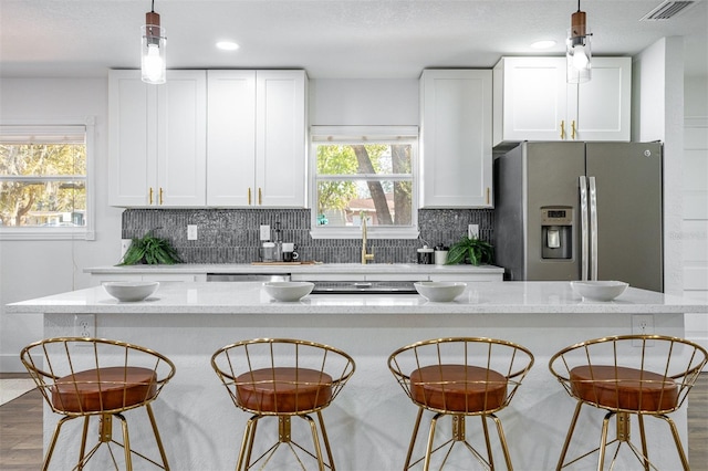 kitchen with a breakfast bar, white cabinets, stainless steel appliances, and decorative backsplash