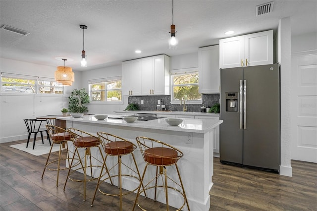 kitchen with dark wood-style floors, decorative backsplash, visible vents, and stainless steel fridge with ice dispenser