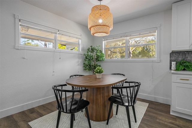 dining space with baseboards and dark wood-type flooring