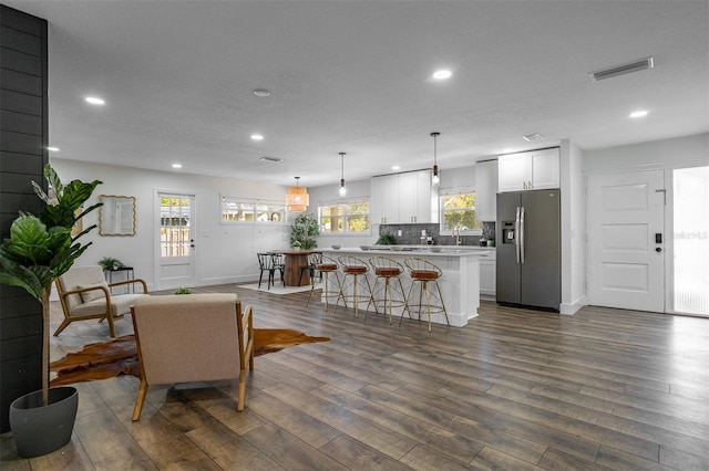 living room with dark wood-type flooring, visible vents, and recessed lighting