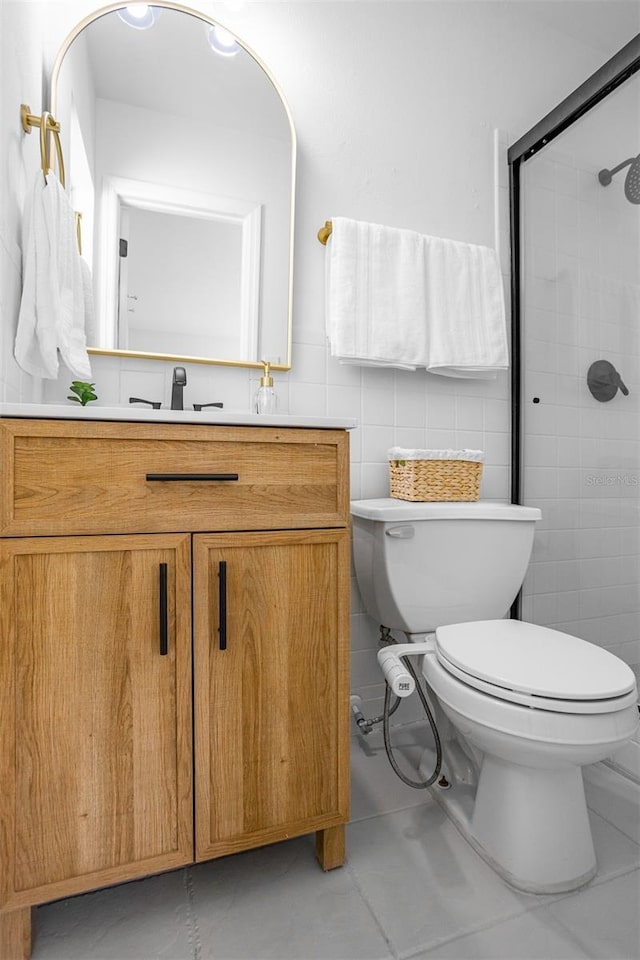 full bath featuring toilet, tile patterned floors, a tile shower, vanity, and tile walls