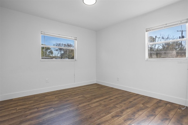 empty room with a healthy amount of sunlight, baseboards, and wood finished floors