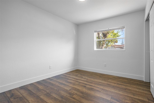 spare room featuring dark wood-style floors and baseboards