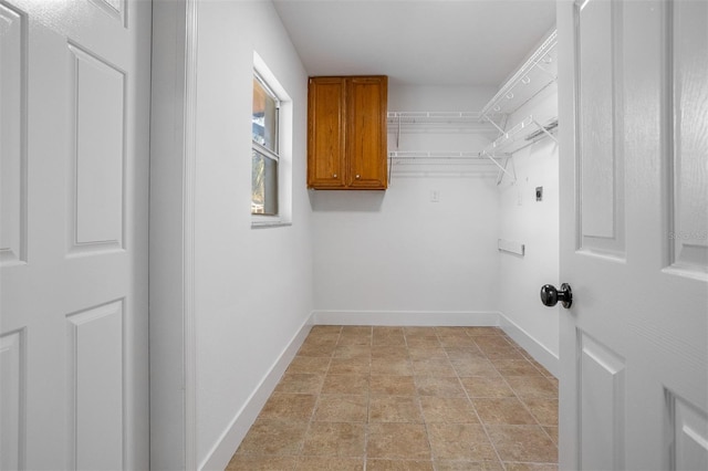 laundry room featuring cabinet space, baseboards, and electric dryer hookup