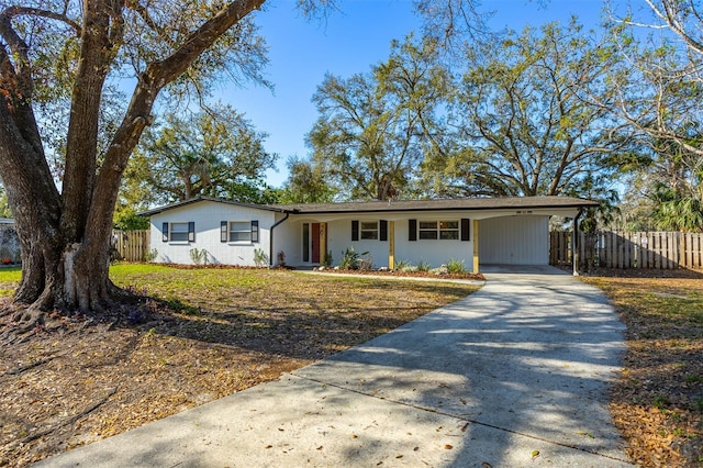 single story home with driveway, an attached carport, and fence