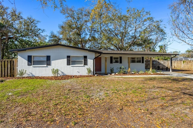 ranch-style house featuring a front yard, fence, a carport, and brick siding