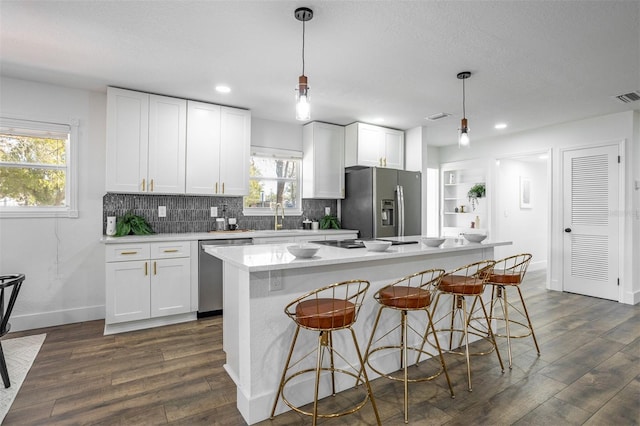 kitchen featuring stainless steel appliances, a breakfast bar, dark wood finished floors, and white cabinets