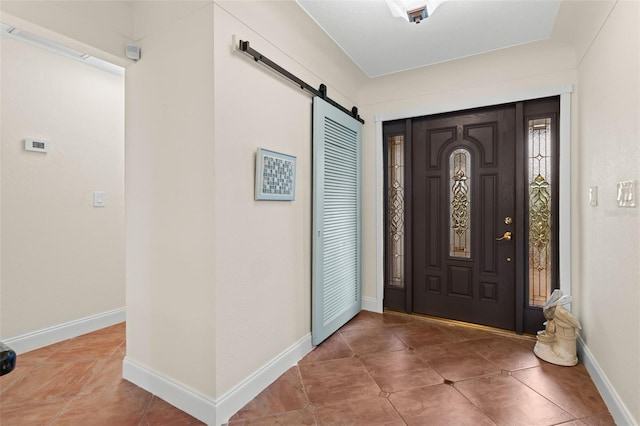 tiled entryway featuring a barn door and baseboards