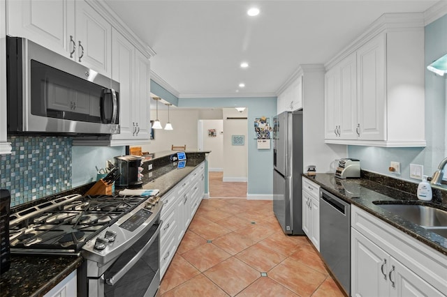 kitchen featuring stainless steel appliances, hanging light fixtures, ornamental molding, white cabinets, and dark stone counters