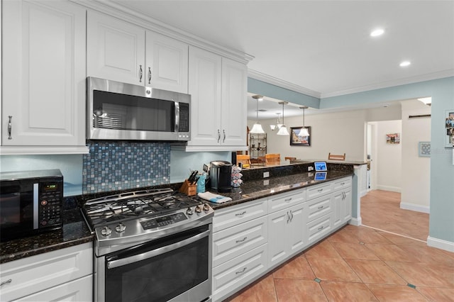 kitchen featuring stainless steel appliances, dark stone countertops, white cabinetry, and pendant lighting