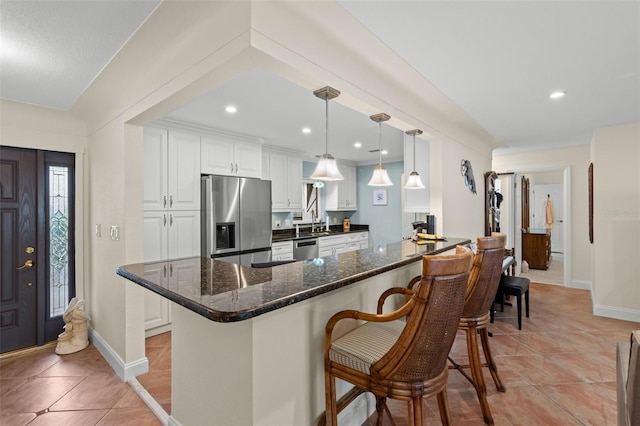 kitchen with white cabinetry, appliances with stainless steel finishes, dark stone countertops, and decorative light fixtures