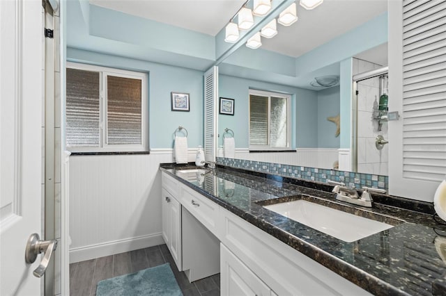 full bath featuring a wainscoted wall, double vanity, a closet, wood tiled floor, and a sink