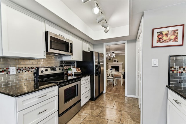 kitchen with a tray ceiling, appliances with stainless steel finishes, backsplash, and white cabinetry