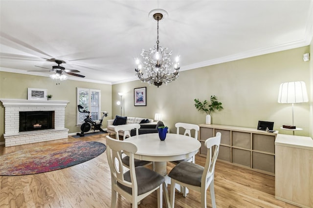 dining space with ornamental molding, light wood-type flooring, a fireplace, and a ceiling fan