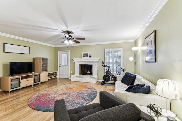 living area with ornamental molding, a ceiling fan, a brick fireplace, and wood finished floors