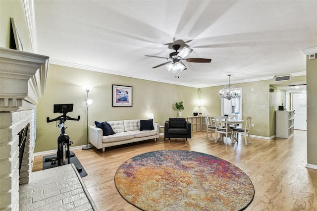 living room with crown molding, a stone fireplace, wood finished floors, baseboards, and ceiling fan with notable chandelier